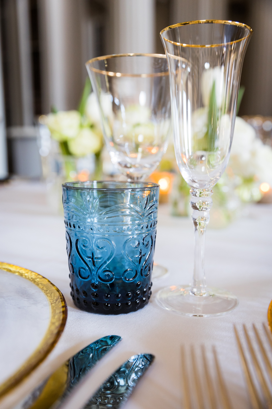 Blue water glass with white Essential linen, gold trim charger plate & gold trim glasses